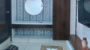 A room with a patterned wallpaper, a wooden door, a white circular mirror, and pink balloons. - HOTEL LOTUS GOLD (Vadodara)