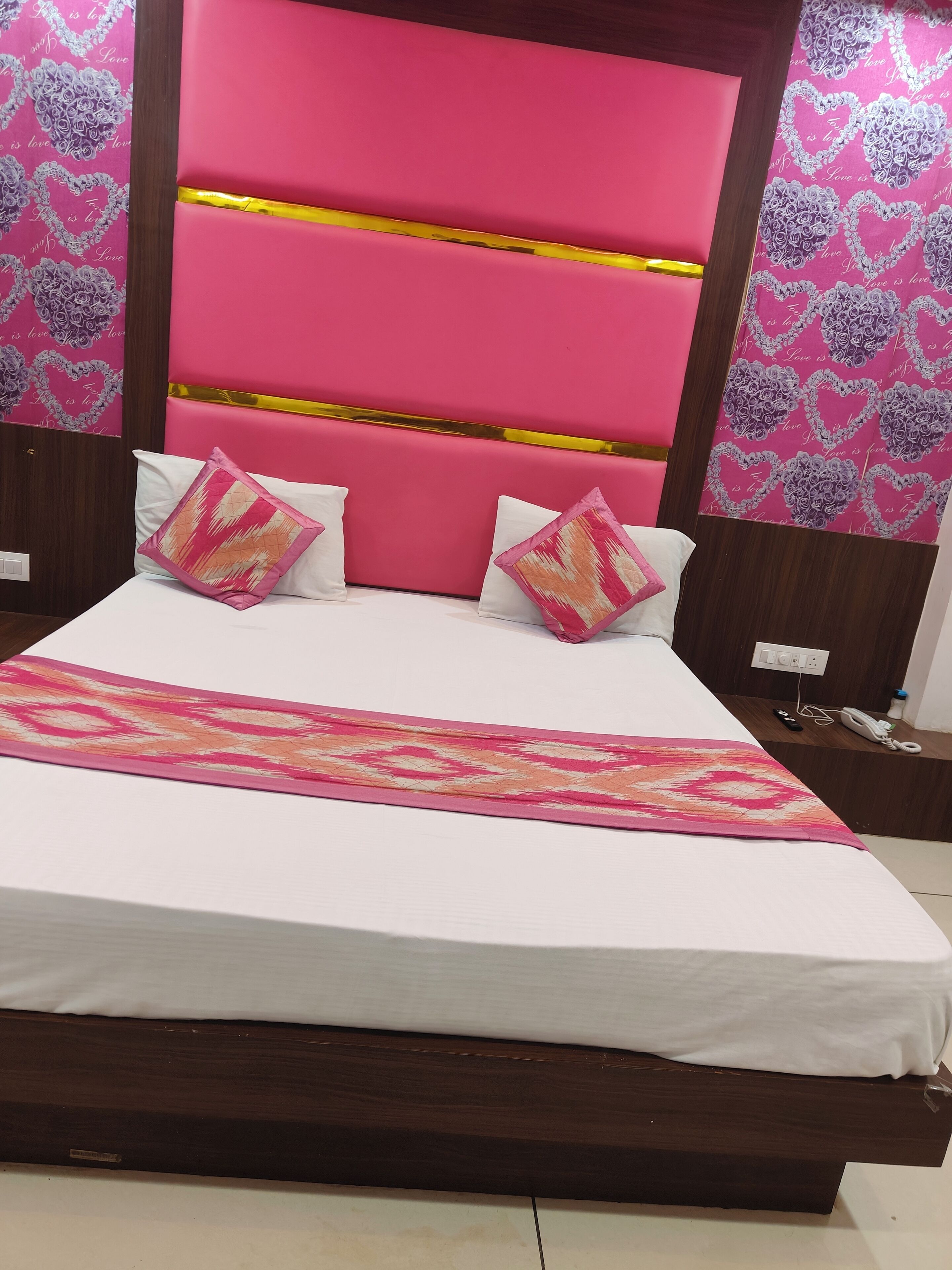 A bed with a white mattress, pink headboard, and decorative pillows.