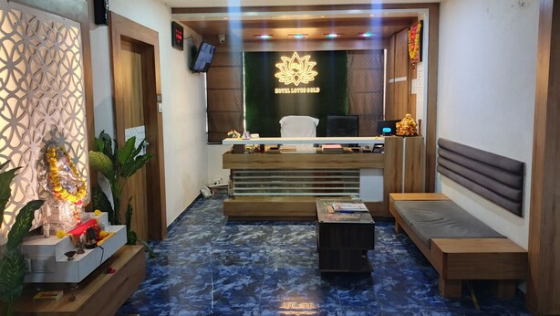 A reception area with a modern design, featuring a reception desk, seating area, and a decorative altar. - HOTEL LOTUS GOLD (Vadodara)