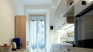 A modern kitchen with wooden cabinets, a built-in oven, and a coffee maker on the counter. - 3-minute walk from Metro Line B, P. Bologna, Tiburtina Station (Airport Link), 2 bedrooms, 2 bathrooms, A/C, Wi-Fi (Roma)