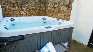 A hot tub with a wooden exterior, a control panel, and a small wooden step leading to the tub. - Curzon Heights (Llandudno)