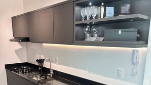 A modern kitchen with a black countertop, stainless steel appliances, and a built-in oven. - Premium Ocean View Penthouse in Meia Praia - 12th floor, high standard, one block from the beach. (Itapema)