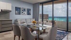 Ein modernes Wohnzimmer mit einem Glastisch, grauen Sofas und Blick auf den Ozean.