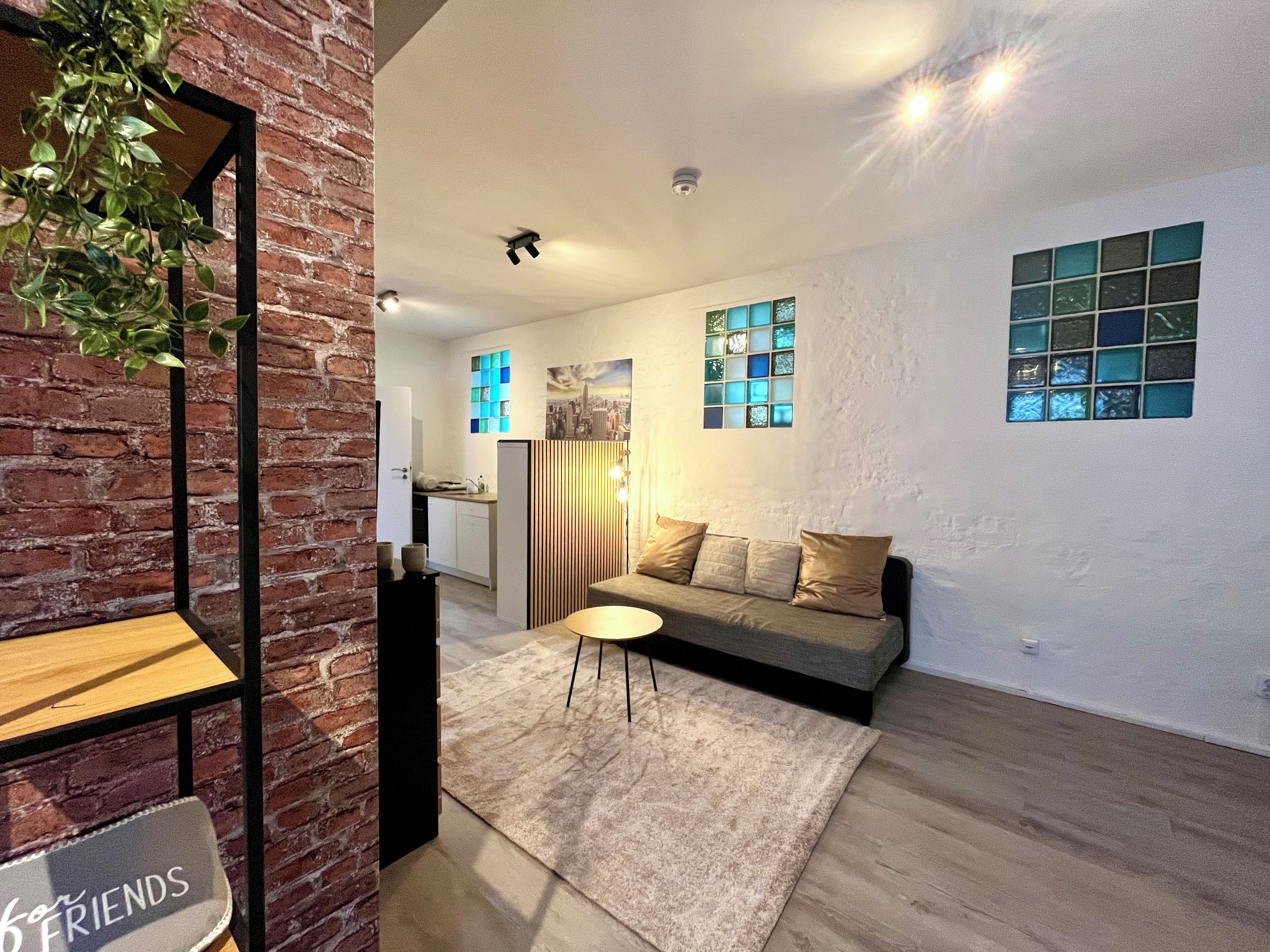 Una sala moderna con un sofá, una mesita y una planta decorativa.