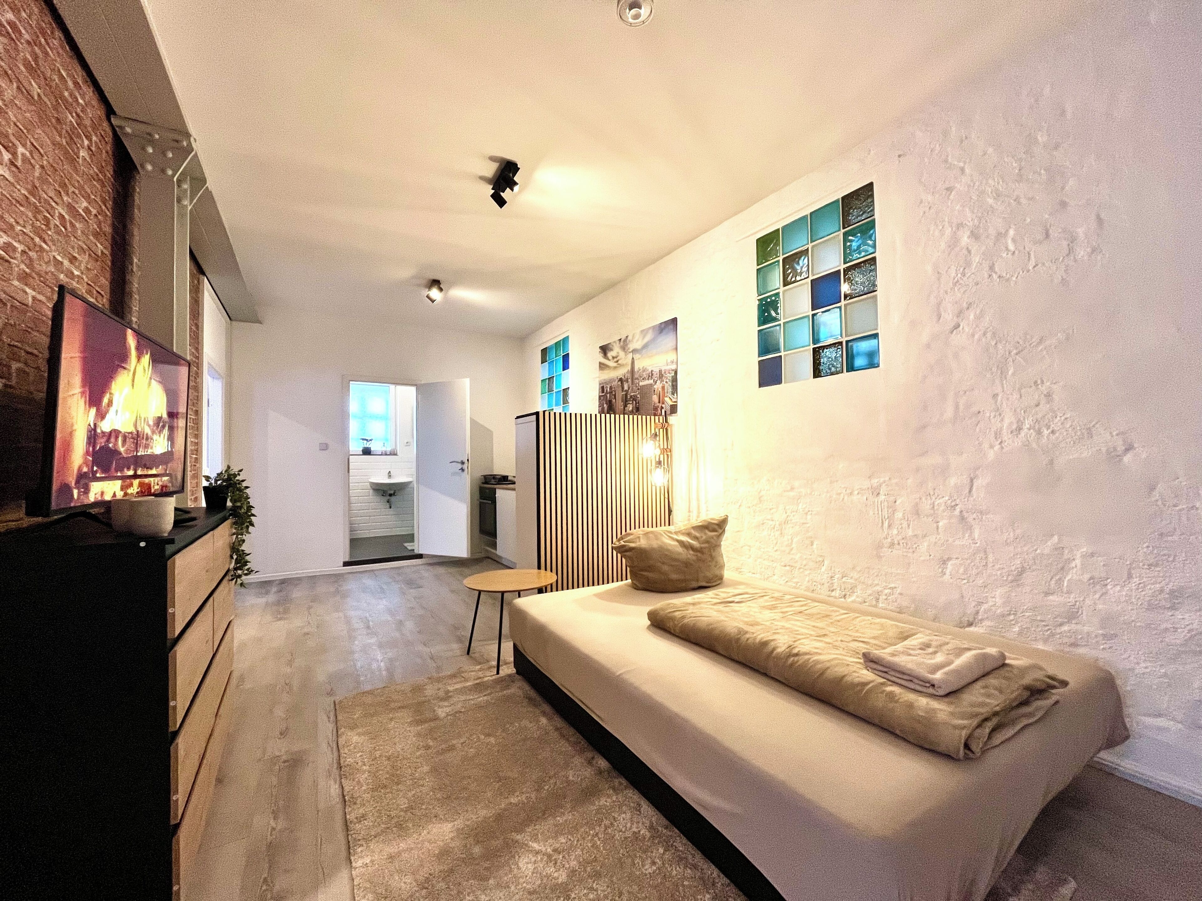 Una sala de estar moderna con sofá, televisión y chimenea.