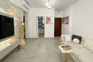 Ein modernes Wohnzimmer mit Flachbildfernseher, einer Couch, einem Couchtisch und einer dekorativen Vase.