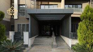 Entrada de un edificio moderno con un vestíbulo cubierto, escalones y un logotipo.