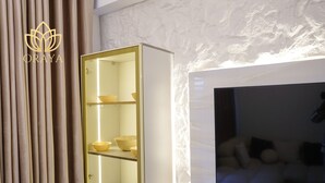 Un interior moderno con un armario blanco de puertas de cristal, un sofá y una pared con un patrón texturizado.