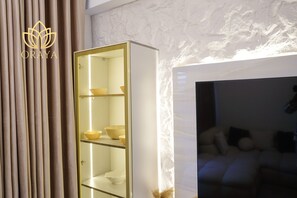 Ein modernes Interieur mit einem weißen Korpus mit Glastüren, einer Couch und einer Wand mit Strukturmuster.