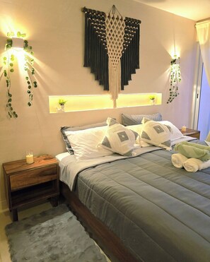 A neatly made bed with pillows and a blanket, a bedside table with a candle, and wall-mounted plants. - Penthouse Studio in the Jungle - Relax & Nature (Tulum)