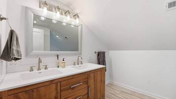 Une salle de bain moderne avec un grand miroir, deux lavabos, un meuble-lavabo en bois et un porte-serviettes.