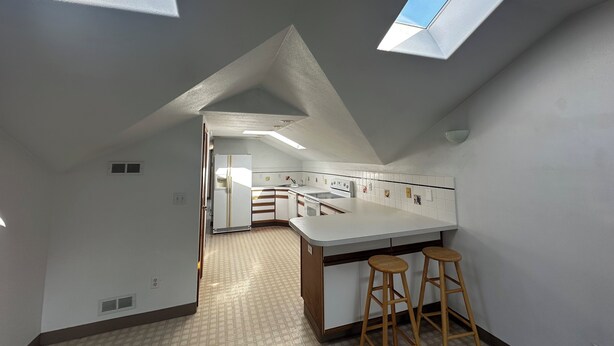 A modern kitchen with skylights, a central island, and bar stools. - 2-bedroom studio sunny bright north hill location. (Pendleton)