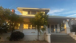 A two-story house with a porch, a chimney, and a number '815' on the front wall. - 2-bedroom studio sunny bright north hill location. (Pendleton)