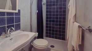 Een badkamer met een wastafel, toilet, douche en spiegel.