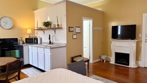 A compact living space with a kitchen, dining area, and a fireplace. - Sunlit Studio on Historic Main Street (Palmyra)