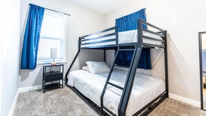 A bunk bed room with a desk and a window with curtains. - Comfortable 3-Bedroom Home in a Great Central Location (Lincoln Park)