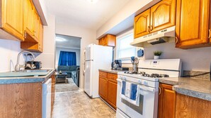 A compact kitchen with wooden cabinets, a built-in oven, and a refrigerator. - Comfortable 3-Bedroom Home in a Great Central Location (Lincoln Park)