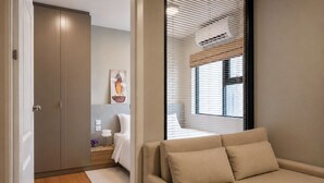 A modern bedroom with a bed, bedside table, and a window with blinds.