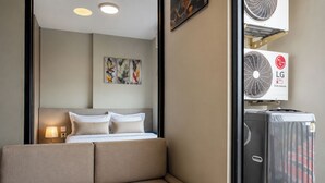 Habitación de hotel con cama, una obra de arte en la pared, lámpara y aire acondicionado inverter doble.