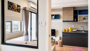 Un apartamento moderno con un ventanal grande, una cocina con armarios azul y marrón, y un comedor con mesa y sillas.