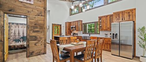 Una cocina amplia con armarios de madera, un refrigerador grande y un comedor con mesa y sillas de madera.