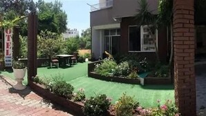 Un hotel con patio, mobiliario exterior y jardín.
