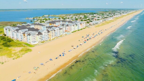 Un hôtel situé sur la côte, composé de plusieurs bâtiments, avec une plage de sable et une vue sur l’océan.