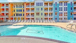 Un hôtel à plusieurs étages doté d’une piscine, de balcons et de chaises longues.