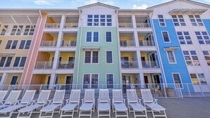 Un hôtel à plusieurs étages, doté de balcons et d’une rangée de chaises longues blanches devant l’entrée.