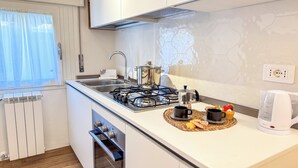 Eine moderne Küche mit Gasherd, Wasserkocher und Kaffeemaschine auf der Arbeitsfläche.