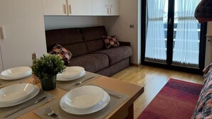 A dining area with a table set for four, a sofa, and a large window with curtains. - Maison Letì Ca-Sa Check (Aprica)