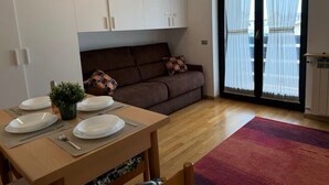 A modern living space with a dining area, a sofa, and a sliding glass door leading to a balcony. - Maison Letì Ca-Sa Check (Aprica)