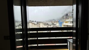 A balcony with a view of a cityscape, including buildings and a mountain in the background. - Maison Letì Ca-Sa Check (Aprica)