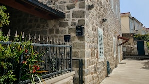 Un edificio de piedra con una puerta de metal y un pequeño jardín.
