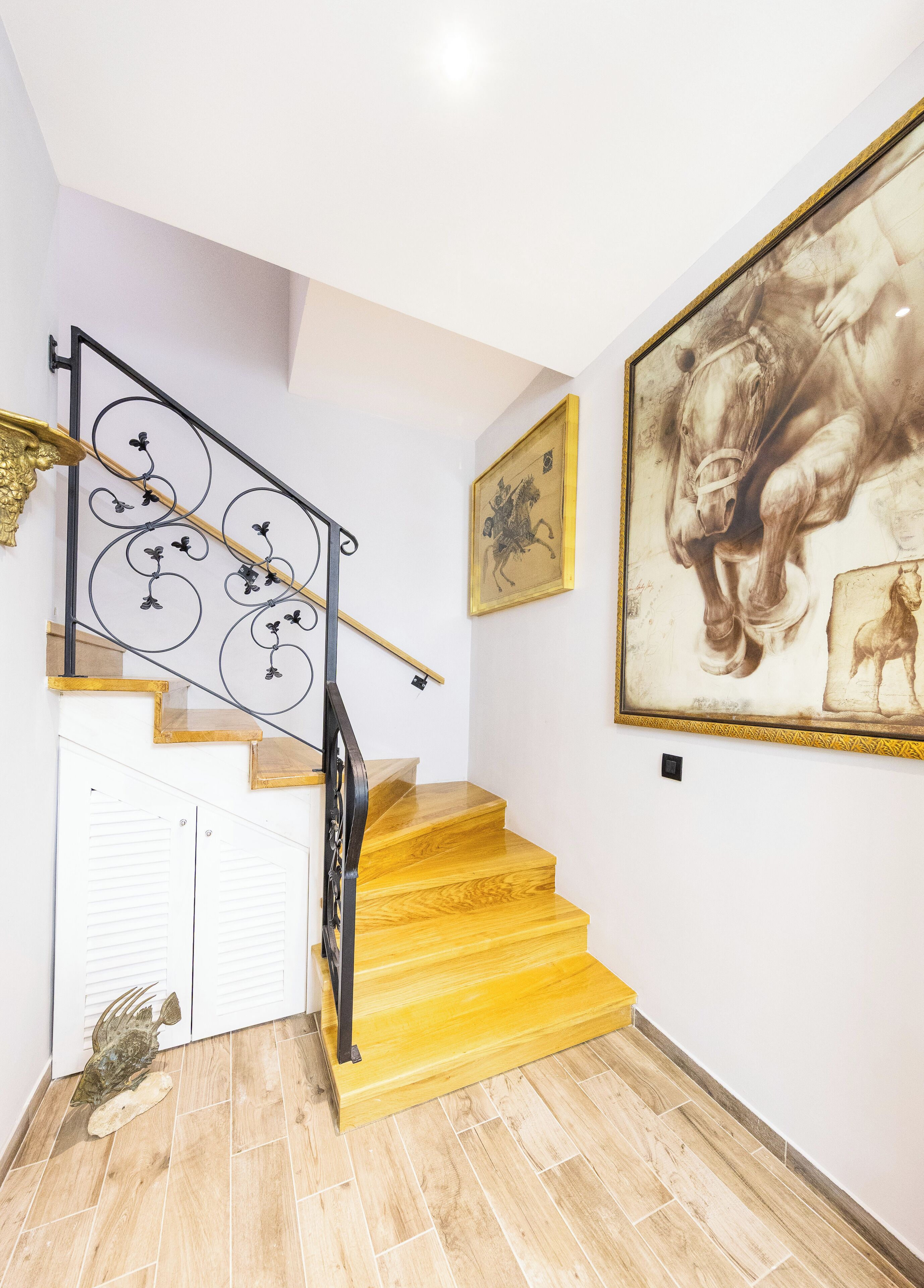 A staircase with wooden steps and a black metal railing, leading to a white door.