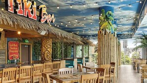 Un restaurant amb temàtica tropical, que destaca per un teulat de palla, columnes de bambú i llums penjants.