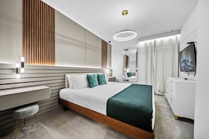 Quarto de hotel moderno com cama, mesa de cabeceira, espelho e televisão.
