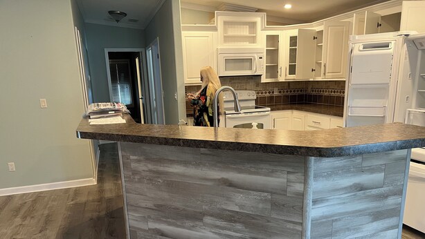 A kitchen with a central island, white cabinetry, and a tiled backsplash. - 2-bedroom 2bath mobile home in lovely Alligator Park Punta Gorda FL with AC (Punta Gorda)