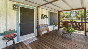 A covered porch with a wooden bench, a small table with a potted plant, and a welcome mat. - Lake Limestone Getaway w/ Firepit (Groesbeck)