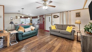 A spacious living area with a wooden floor, two sofas, a ceiling fan, and a dining table. - Lake Limestone Getaway w/ Firepit (Groesbeck)