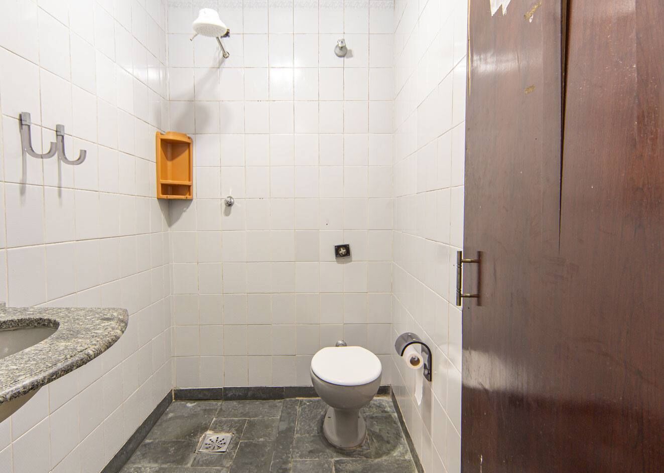 A small, tiled bathroom with a toilet, a sink, and a shower.