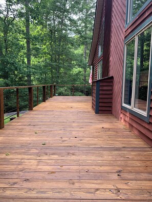 Eine Holzterrasse mit Geländer, umgeben von Bäumen.