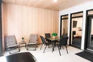 A modern interior with a wooden wall, a glass door leading to a living area, and a dining table with chairs. - Lynx Spa et confort à Orford (Orford)