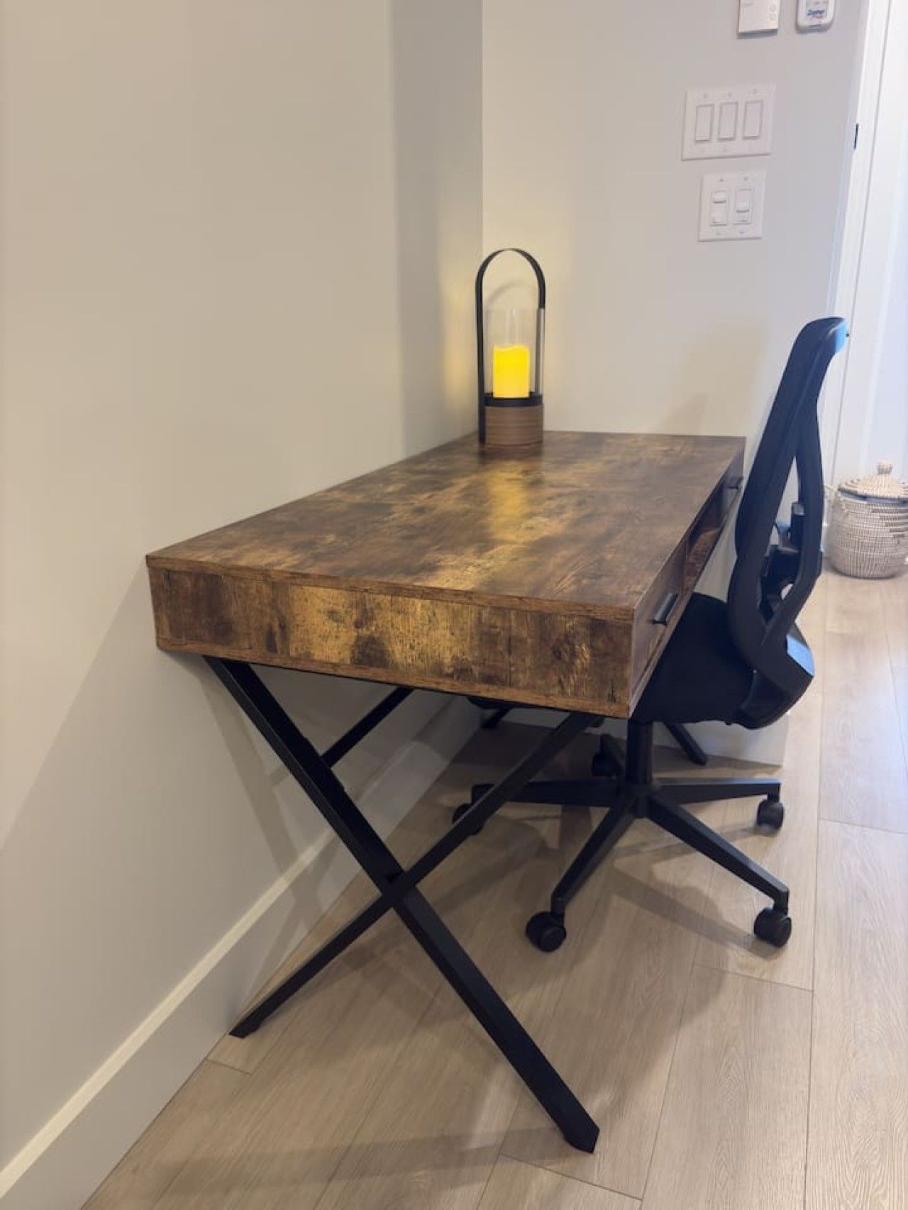 Un bureau en bois avec un plateau en verre et une chaise de bureau noire.