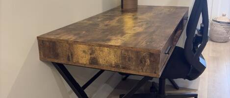 Un bureau en bois avec un plateau en verre et une chaise de bureau noire.