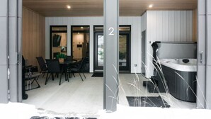 A modern interior with a dining area, a kitchen, and a hot tub. - Lynx Spa et confort à Orford (Orford)