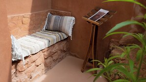 A small, cozy reading nook with a bench and a wooden stand holding a book. - HOTEL POSADA LAS RETAJAS (Medinaceli)