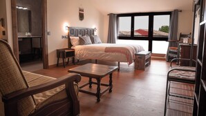 A bedroom with a large bed, a wooden chair, a small table, and a desk. - HOTEL POSADA LAS RETAJAS (Medinaceli)