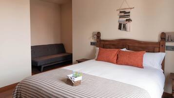 Een net opgemaakt bed met een gestreept laken, een nachtkastje en een decoratief object aan de muur.