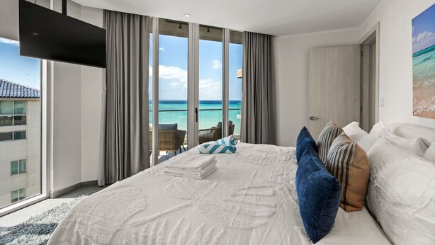 Ein modernes Hotelzimmer mit einem großen Bett, einem flachbildfernseher an der Wand und einem Balkon mit Meerblick.
